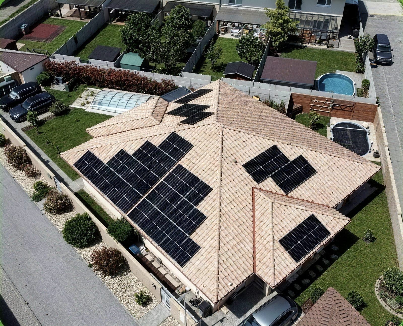 Family home with solar panels on a gable roof and a swimming pool, drone view