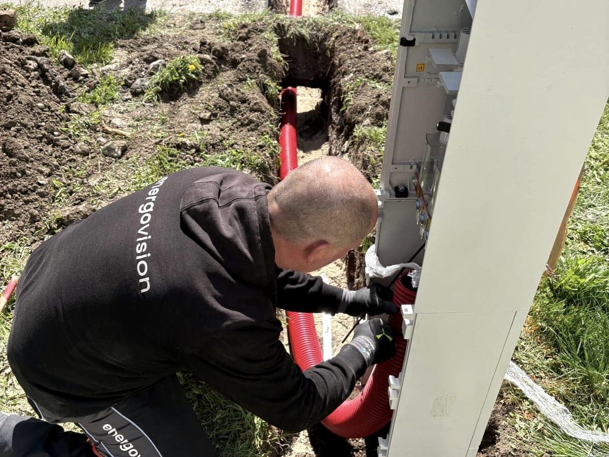 Energovision electrician connecting a cable in a conduit to a new meter pillar next to a trench