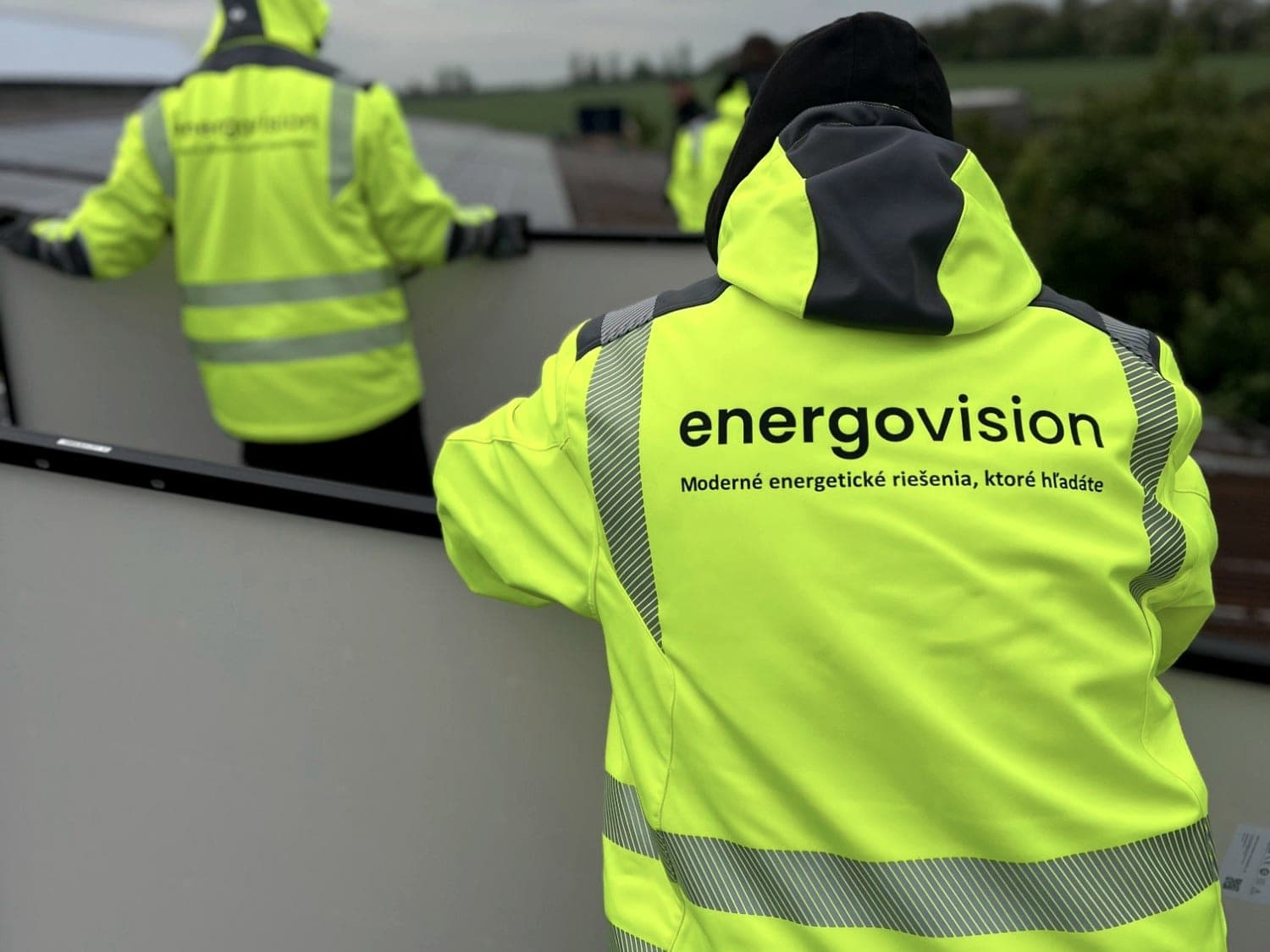 Energovision installation crew in high-visibility jackets fitting panels on a roof