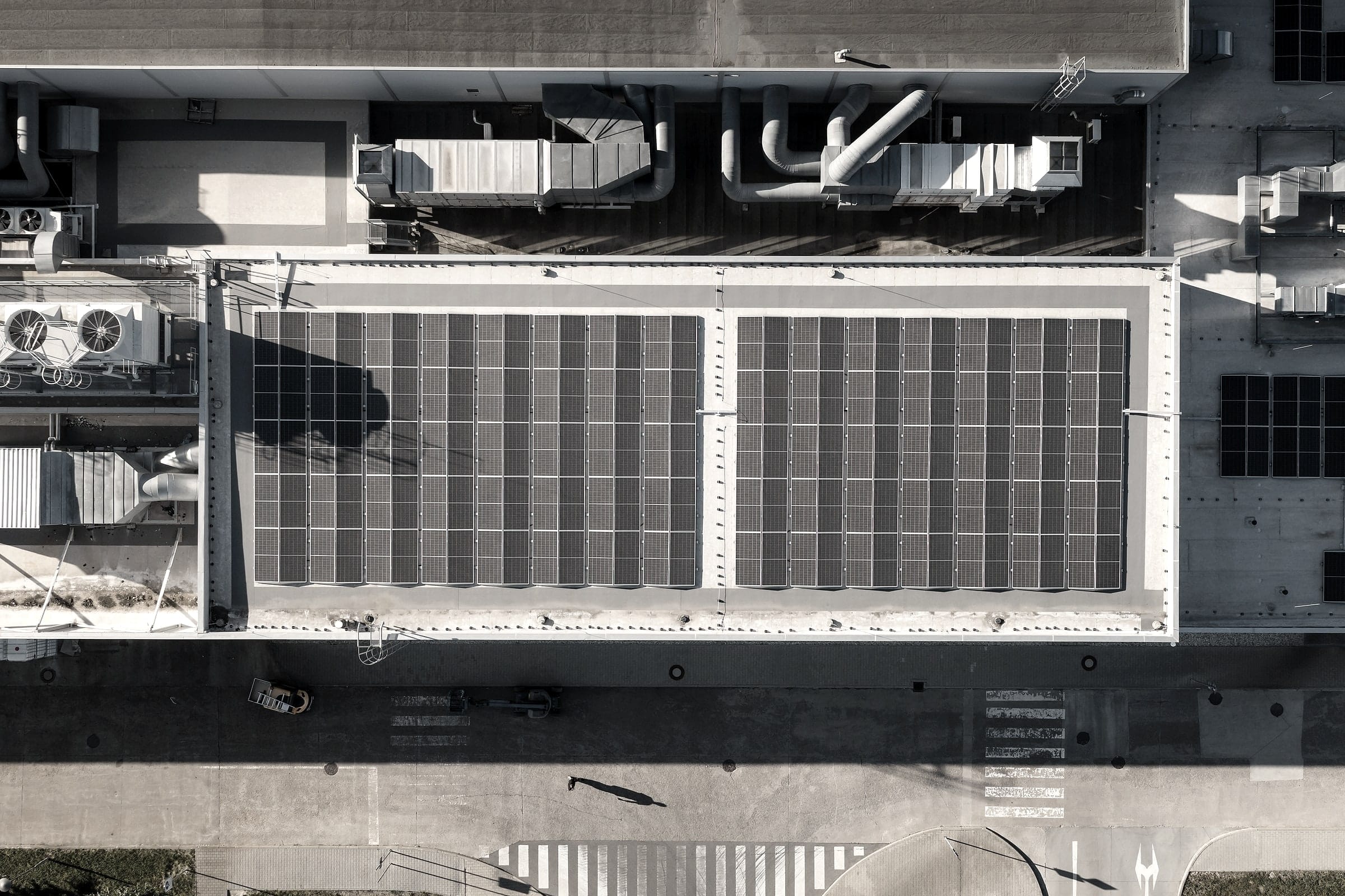 Top-down aerial view of a production hall roof with two fields of solar panels