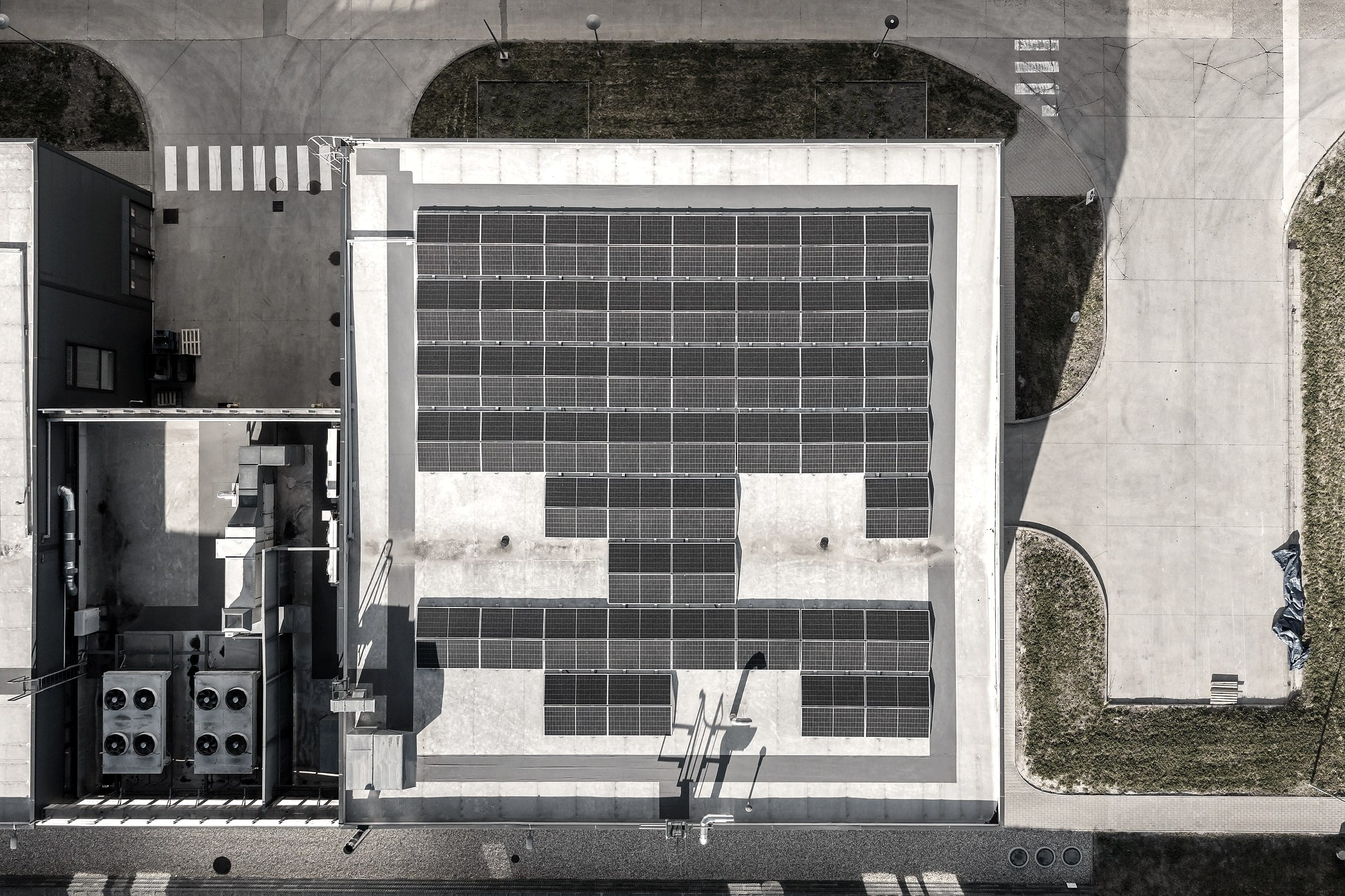 Top-down aerial view of a hall roof with solar panels, cooling units next to it