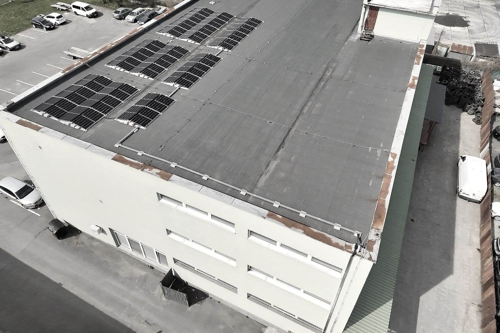 Aerial photo of a building with solar panels on the roof and a car park