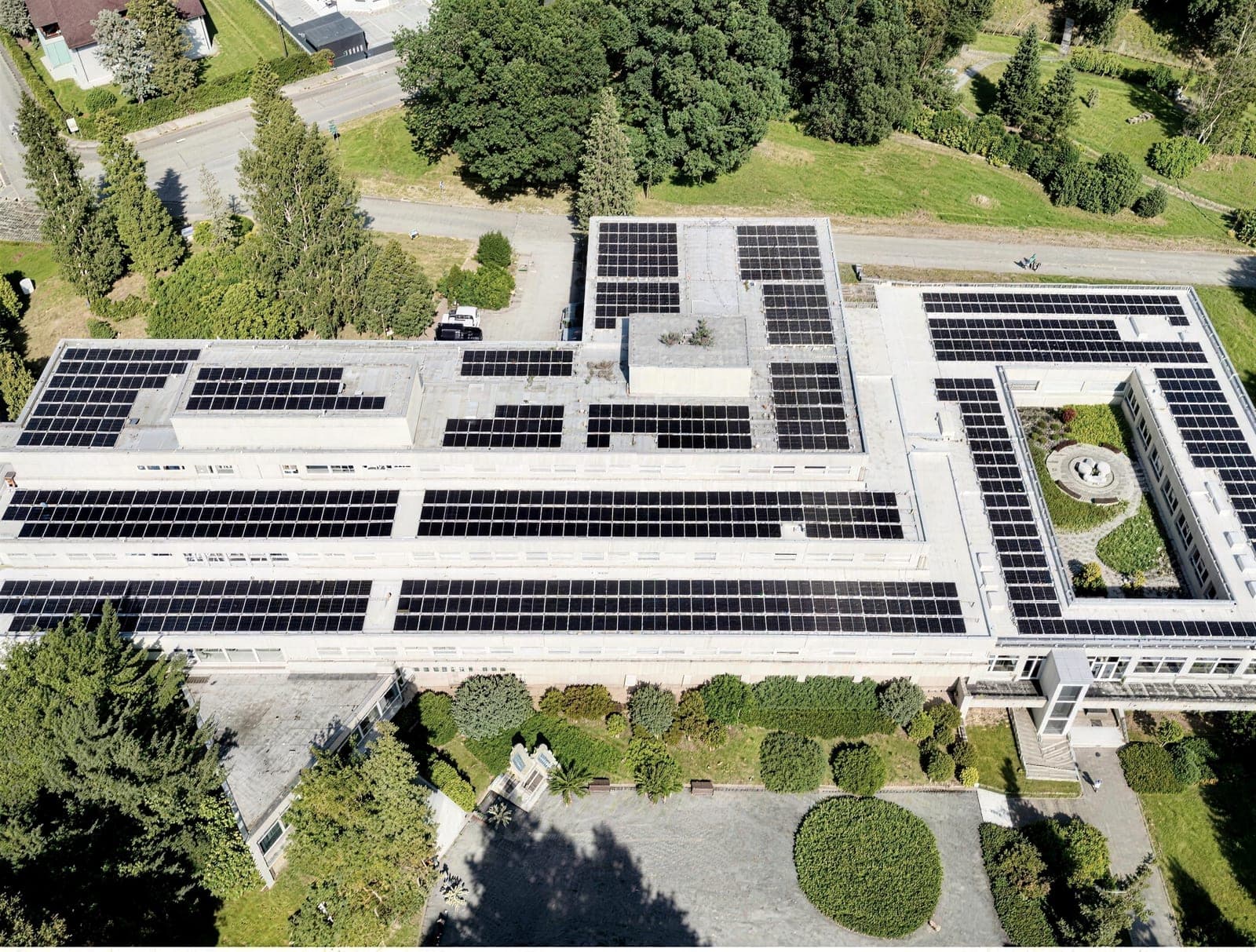 Production hall with solar panels on the roof surrounded by greenery