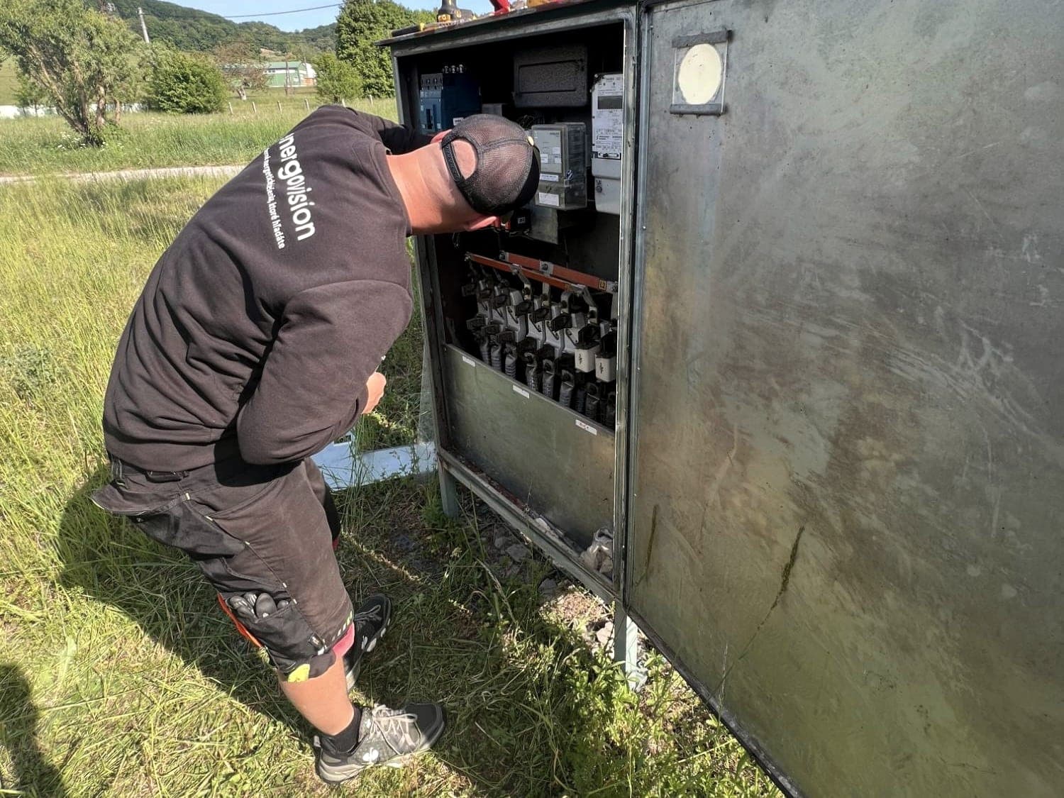 Energovision electrician working on the LV switchboard of a pole-mounted transformer station